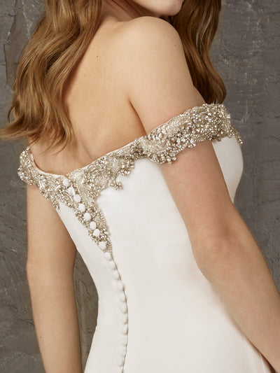Pronovias Newton is a crepe mermaid dress with a long train, plunging v and off-the-shoulder straps.