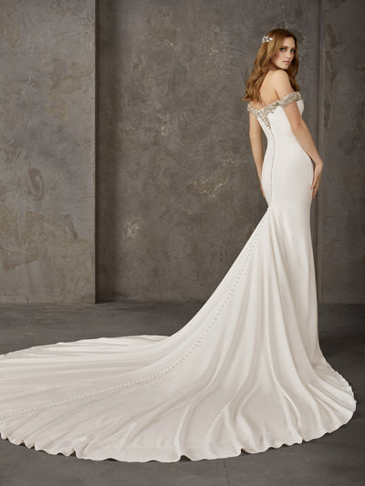 Pronovias Newton is a crepe mermaid dress with a long train, plunging v and off-the-shoulder straps.